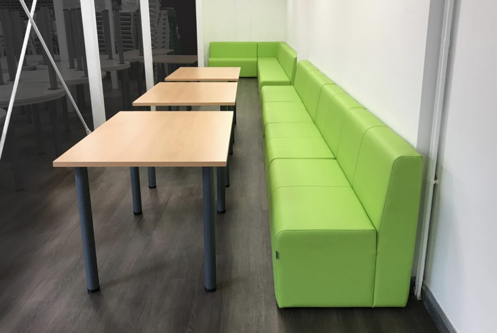 School common room with green modular seating in breakout area
